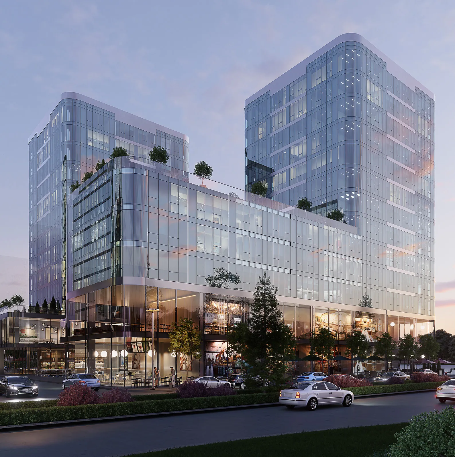 Two glass office towers on a podium at dusk